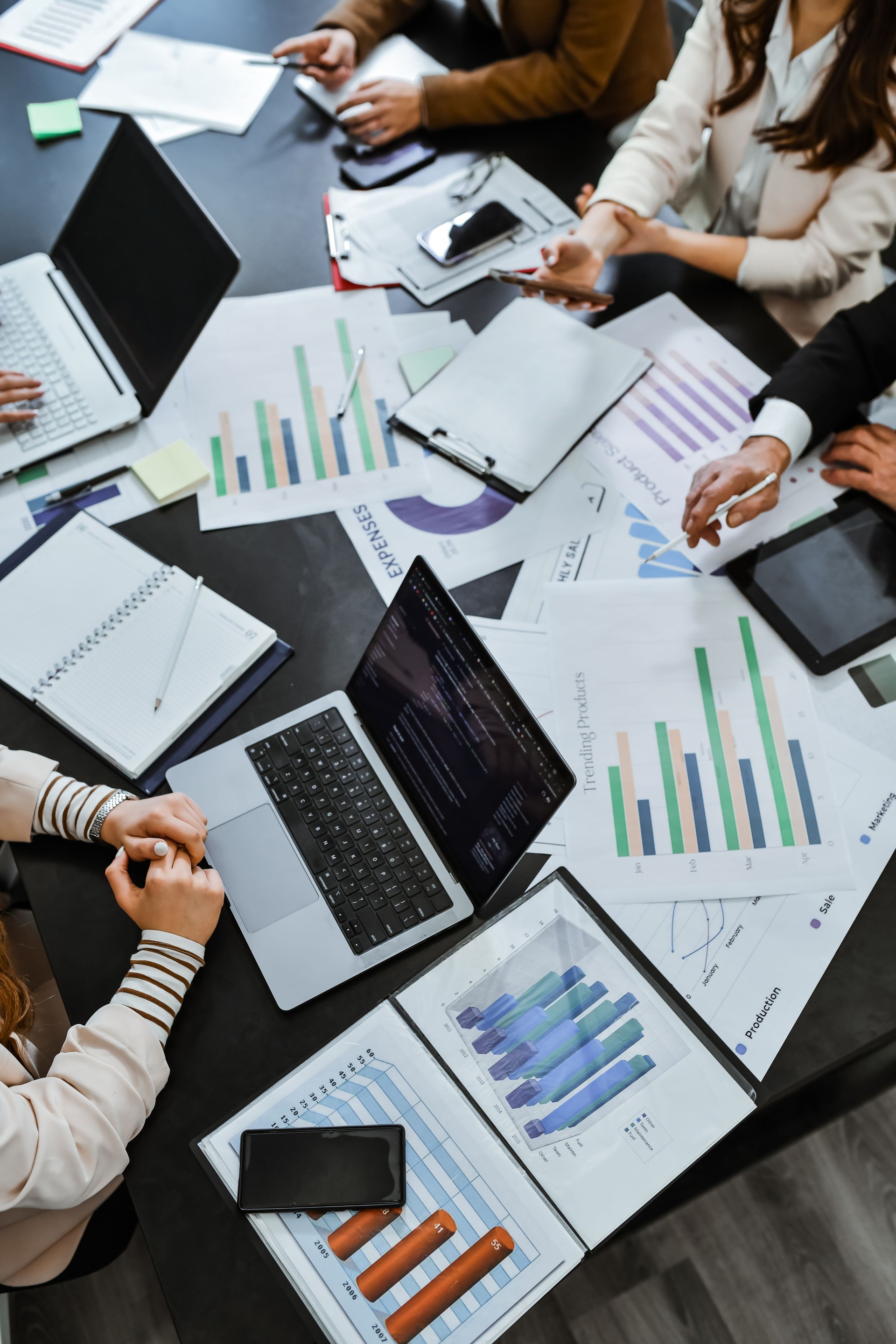 Conference Table Cluttered With Documents And Graphs While Employees Are Having Monthly Meeting